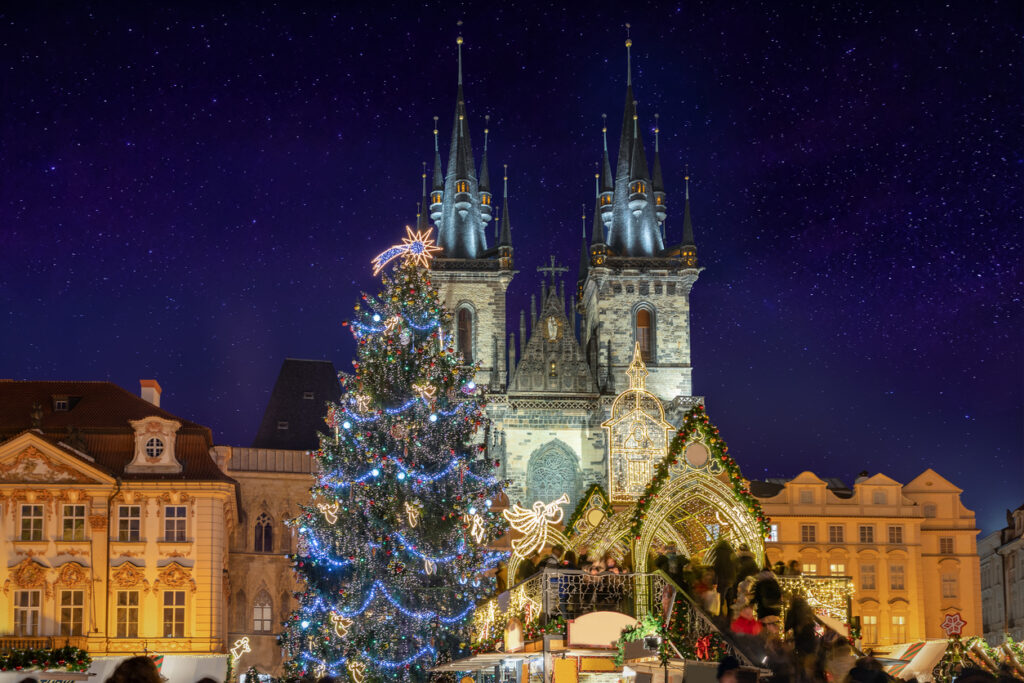 Beautiful view to the christmas market and tree at the old town square of Prague, Czech Republic, in front of the iconic Tyn Church with a starry sky