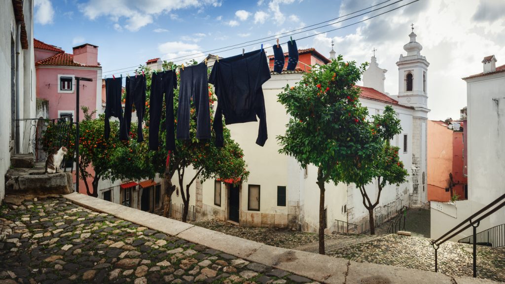 A view of the church and Largo de Sao Miguel, small square in the historical district of Alfama, Lisbon, Portugal, with hanging laundry and a lone cat