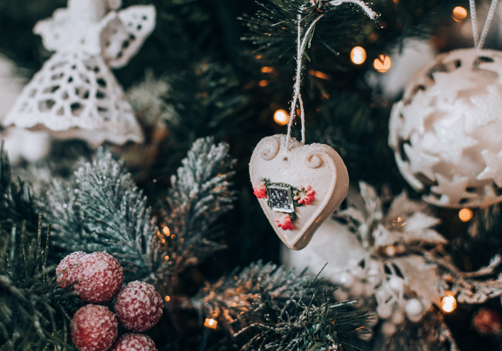 Heart shaped ornament hanging on a decorated christmas tree at home.
