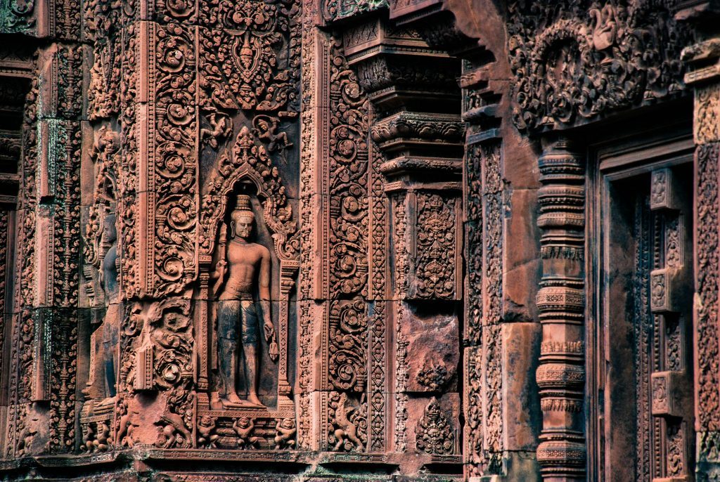 Détails des sculptures en grès rose du temple de Banteay Srei, représentant une statue et de fines gravures de l'art khmer. Siem Reap, Cambodge.