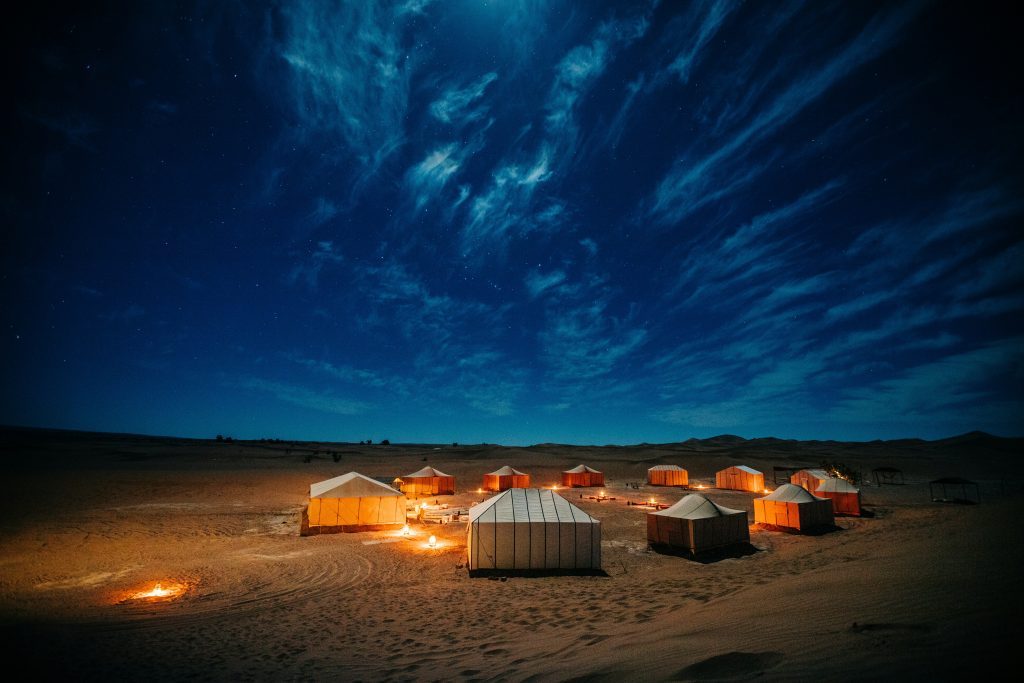 Bivouac éclairé aux lanternes sous un ciel étoilé dans le désert du Maroc, près des dunes de l'Erg Chegaga