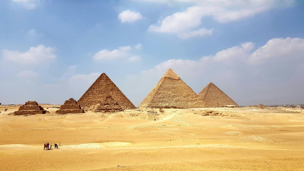Vue panoramique des pyramides de Gizeh, dont la Grande Pyramide de Khéops, au cœur du désert sous un ciel nuageux. Le Caire, Égypte.