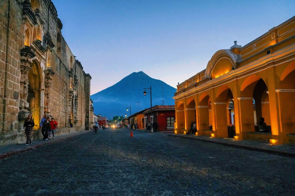 Rue pavée du centre historique d'Antigua avec l'église La Merced et le volcan Agua en arrière-plan au crépuscule. Antigua Guatemala, Guatemala.